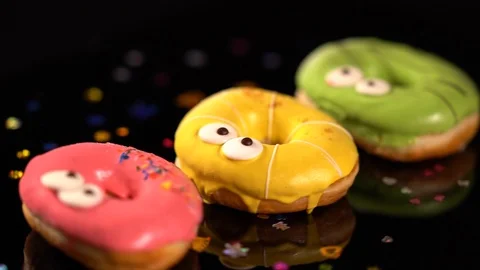 Three spinning colorful iced ring donuts Video stock 96313151