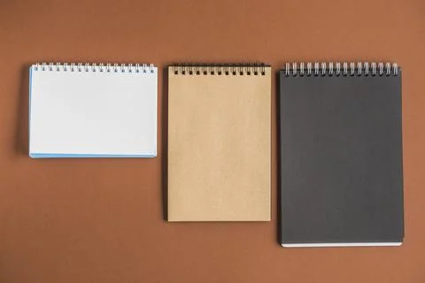 Three spiral notebooks brown backdrop Stock Photos