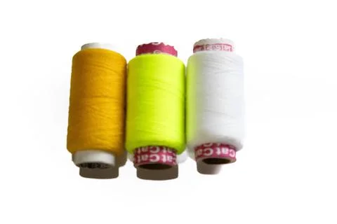 Three spools of colored thread on plastic bobbins yellow green white Stock Photos