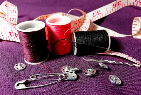 Three spools with multicolored threads and pins are lying on a purp Stock Photos