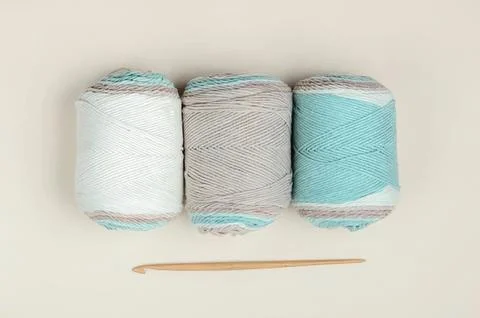 Three spools of pastel-colored thread with a sewing needle Foto stock