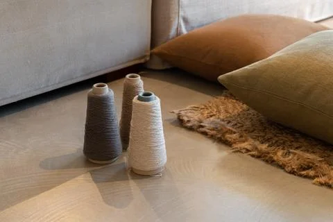 Three spools of thread in neutral colors placed on a wooden floor near soft Stockfoto's