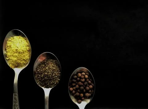 Three spoons with spices on black background Stock Photos