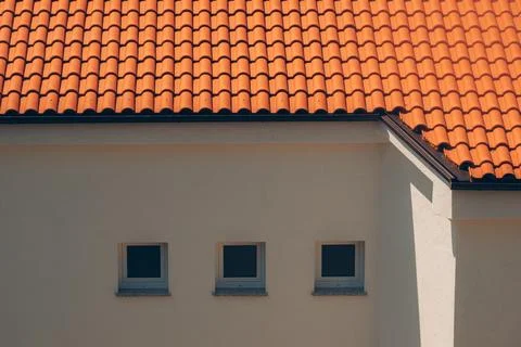 Three square windows lined up on a neutral stucco building wall under an or.. Stock Photos