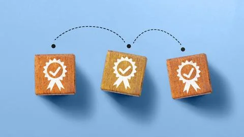 Three square wooden blocks featuring a white quality badge icon with checkm.. Stock Photos