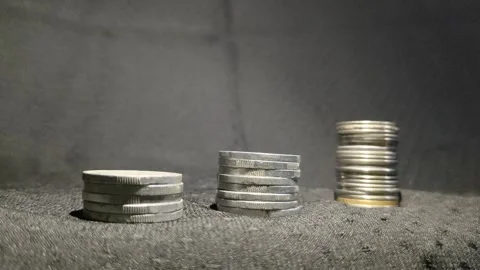 Three stack of coins aligned to form a revenue growth graph with moving light Stock Footage 287051757