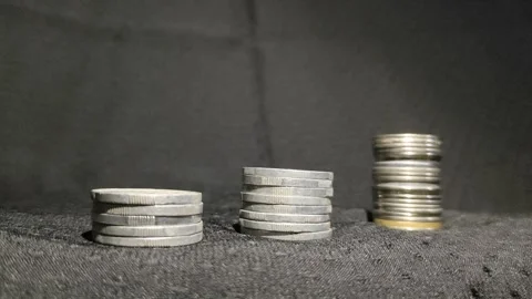 Three stack of coins aligned to form a revenue growth graph with moving light Stock Footage 287051765