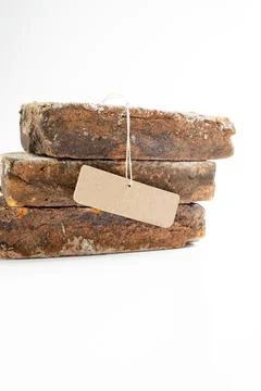 Three stacked rustic, weathered bricks with a blank brown paper label, isol.. Stock Photos