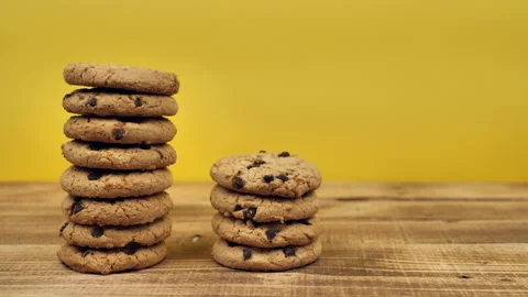 Three stacks of chocolate oatmeal cookies trim on a wooden table with a yellow Stock Footage 166419902