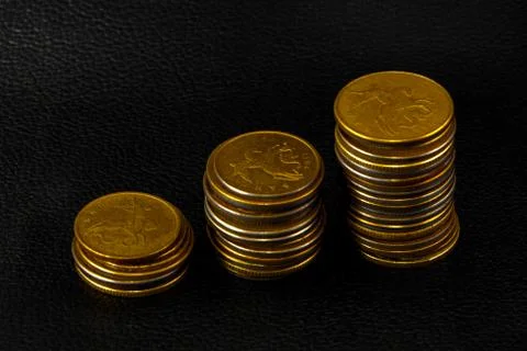 Three stacks of coins on black leather Stock Photos