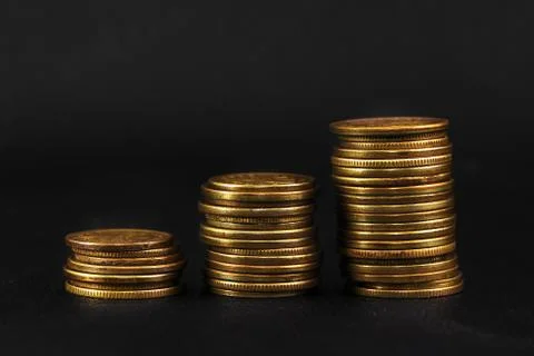 Three stacks of coins on black leather Stock Photos