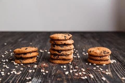 Three stacks of crisp chocolate chip cookies on a dark wooden table Foto stock