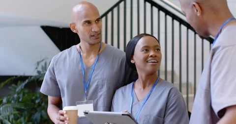 Three staff in scrubs at clinic steps woman leading tablet review coworker Stock Footage 344383931