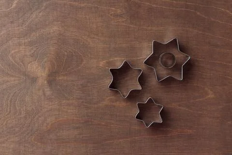 Three star-shaped cookie cutters on the dark brown wooden background, horizon Stock Photos