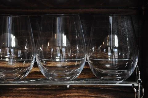Three stemless wine glasses on brown wine rack Foto stock