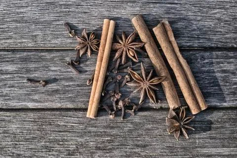 Three sticks of cinnamon, four star fruit of star anise and cloves on old boa Stock Photos