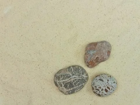 Three stones on sand background Stock Photos