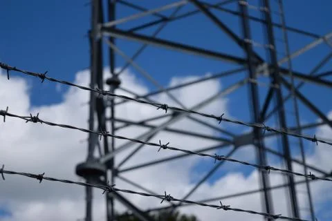 Three Strands of Barbed Wire with Tower in Background Stock Photos
