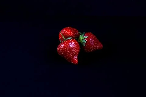 Three strawberries on a black background Stock Photos