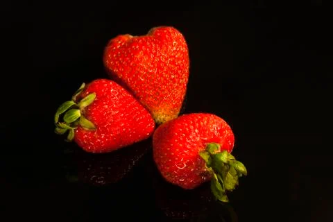 Three strawberries on black Stock Photos