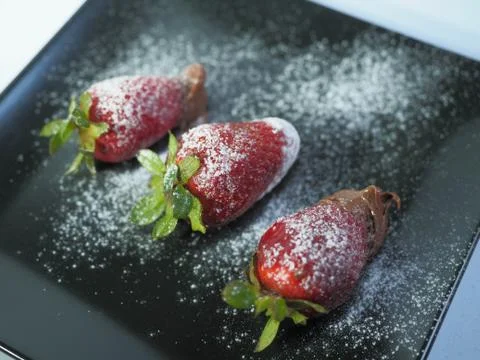 Three strawberries  with icing sugar from back Stock Photos