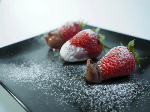 Three strawberries with icing sugar close up Stock Photos