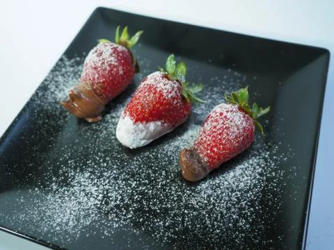 Three strawberries with icing sugar front view Stock Photos