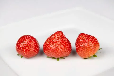 Three strawberries on a plate Foto stock