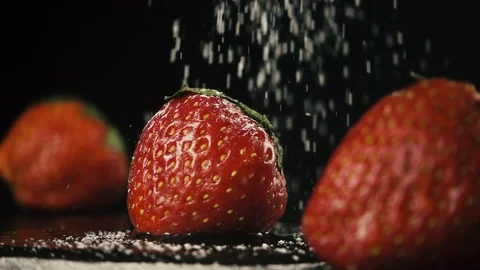 Three strawberries in a row on a black table. Slow mo Stock Footage 75480519
