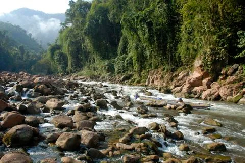 Three strong young men pull and push a wooden boat up the nam ou river, white Stock Photos