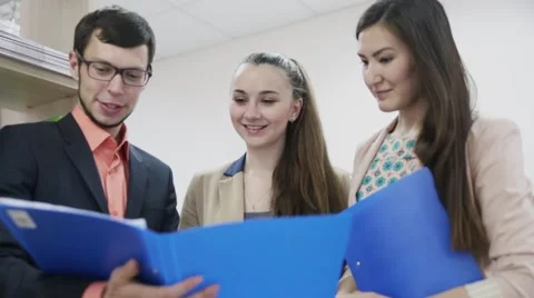 Three students communicate young businessman looking at documents in folders Stock-Footage 63116024