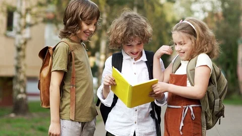 Three students look at the book and laugh gaily. Children's Day. Back to school Stock Footage 89607852