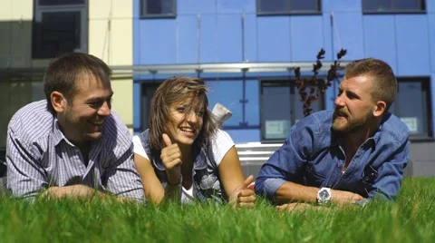 Three students lying on the lawn dabble Stock Footage 67833484