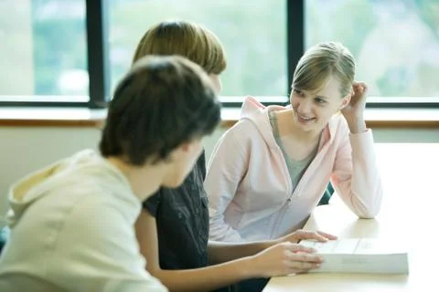 Three students sitting at table, chatting Stock Photos
