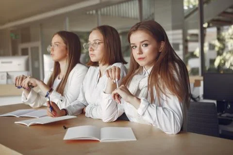 Three students sitting at the table in a class Stock Photos