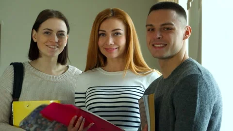 Three students smiling together in a college lecture hall Stock Footage 311944129