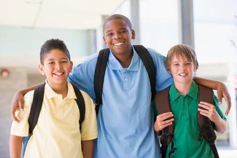 Three students standing outside school together smiling (high key) Stock Photos