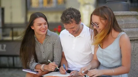 Three Students Studying Outdoors and Laughing Together During Warm Sunny Day in Stock Footage 79932582