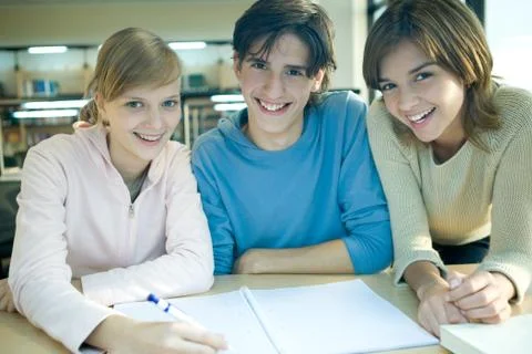 Three students studying together, smiling at camera Stock Photos