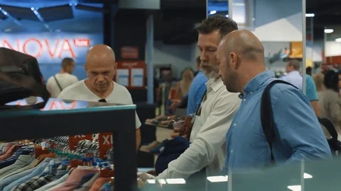 Three stylish men choose for themselves new clothes in the big store Stock Footage 83214767