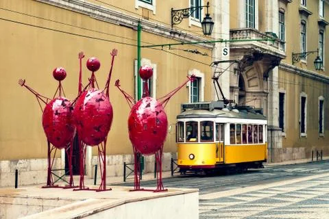 Three stylized statues of red happy men and the Lisbon tram, Portugal Foto stock