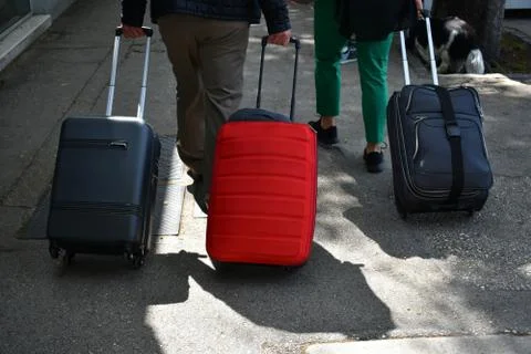 Three suitcases being pulled on the sidewalk in the city Photos