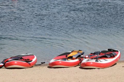 Three SUP boards on a sandy beach near the water 스톡 사진