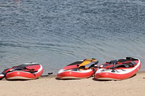 Three SUP boards on a sandy beach near the water 스톡 사진