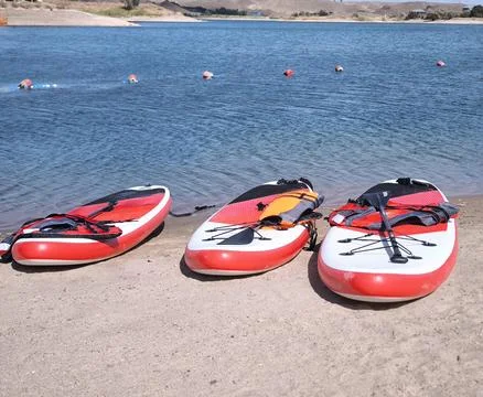 Three SUP boards on a sandy beach near the water 스톡 사진