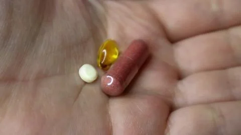 Three supplements in an open hand, showcasing their diverse forms and colors. Stock Photos
