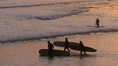 Three surfers enter water Видео 101267241