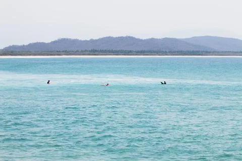 Three surfers wait for a wave in the turquoise waters of Chacahua bay Stock Photos