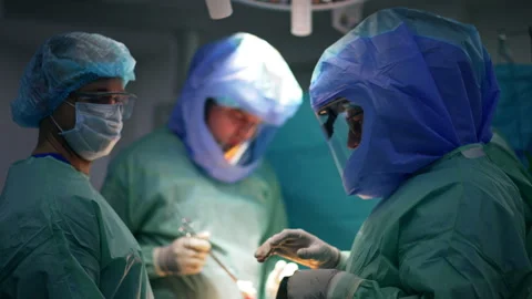 Three surgeons wear protective suits and helmets at operation. Stock Footage 241124950