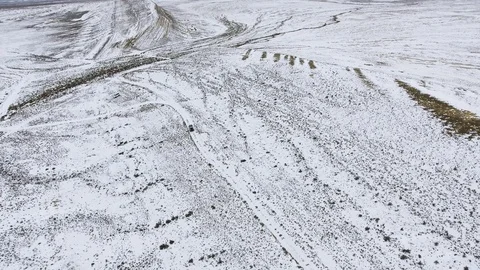 Three SUVs moving along the edge of a sandy cliff of the snow-covered desert in Stock Footage 93996125